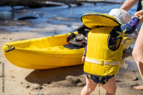 toddler wearing a lifejacket in a kayak on a sandy beach on holiday in summer in australia photo
