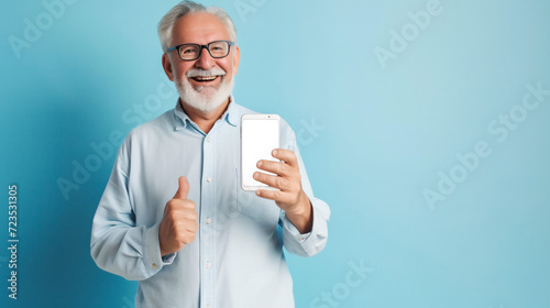 Smiling senior man showing phone with transparent display and giving thumbs up on a blue background, endorsing technology. AI Generative photo