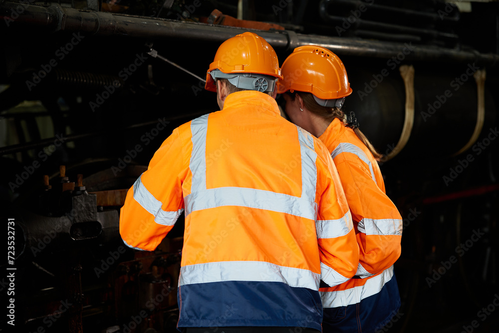 back view engineers or technicians using checking under train construction at station