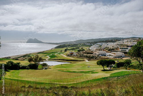 Sotogrande, Spain - January, 23, 2024 - A golf course overlooking the sea with the Rock of Gibraltar in the distance and residential buildings to the side.