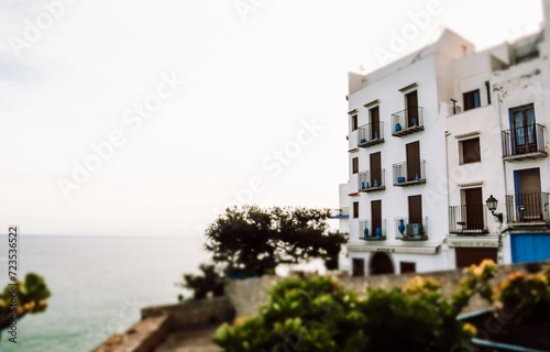 Fototapeta Naklejka Na Ścianę i Meble -  White hotel building on the edge of a cliff against a blue sea. A holiday dwelling with seascape view. Travel destination. Summer vacation postcard.