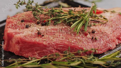 Fresh marbled beef with pepper, salt and rosemary close-up macro. Preparation to cook juicy steak on grill. Premium organic raw wagyu meat photo