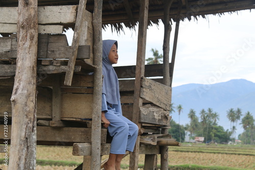 Little girl sitting in a hut in a rice field area in a village in Indonesia photo