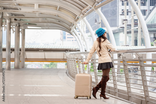 Young female traveler with a suitcase at the modern transport stop outdoors