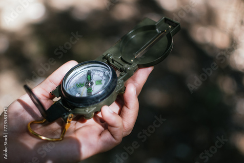 Hand holding a green compass in the forest