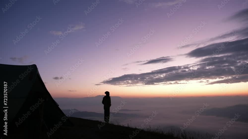 Silhouette of a woman on campground looking at a beautiful sea of fog before sunrise Silhouette of a woman on campground looking at a beautiful sea of fog before sunrise