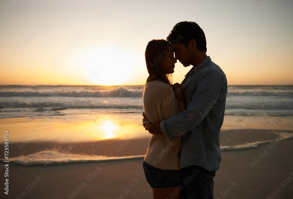 Couple, sunset and hugging on beach vacation, love and bonding on trip to ocean at dusk. People, embrace and romance on outdoor adventure at sea, peaceful environment and commitment in marriage