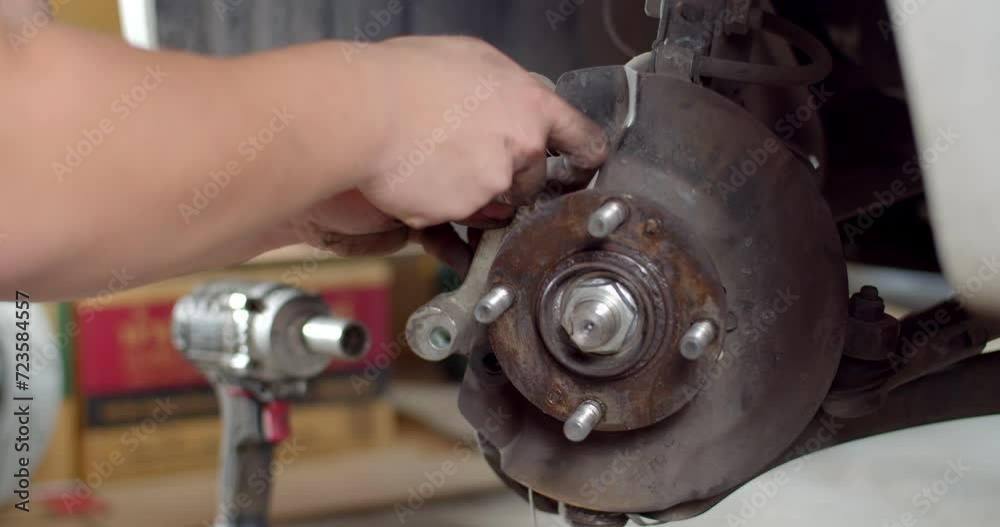 Close-up male hands Installs the brake caliper after replacing the brake pads.Service tech installs the brake caliper back onto a vehicle during routine maintainance.4K60P. Close-up male hands Installs the brake caliper after replacing the brake pads.Service tech installs the brake caliper back onto a vehicle during routine maintainance.4K60P.