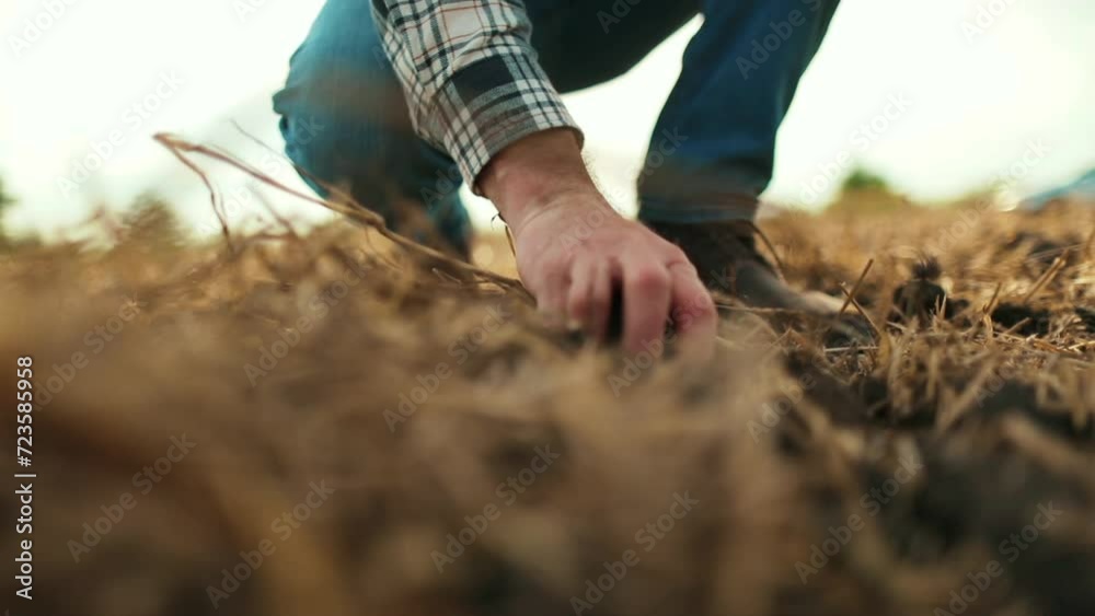 The farmer checks the quality of the soil before planting. A farmer tests the land with a tablet in his hand. Male hands touching soil on field.