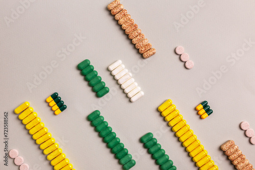 Different colored tablets and pills are laid out in a line on a light background top view.