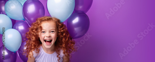 Laughing little girl with purple and blue balloons.