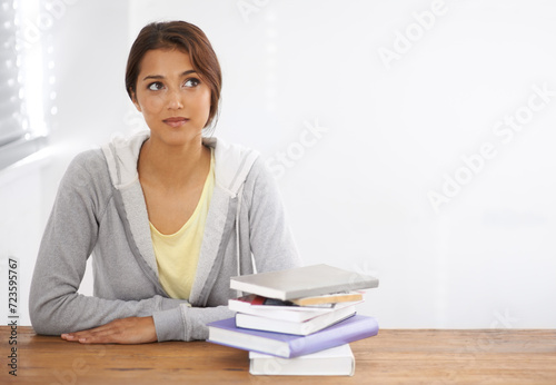 Woman, student or thinking with books by desk, idea or learning for research of assignment. Young person, indian and thought by notebook on scholarship, studies and planning for test study in college