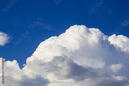 Huge fluffy cumulus cloud on blue sky. Formation before thunderstorm. Copy space