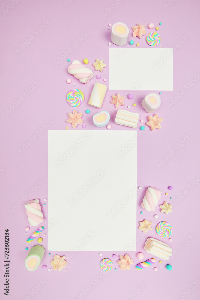 Set of two blank white cards on cute pastel purple kawaii background with frame of sweet candies, meringue and marshmallows . Flat lay, top view, copy space. Beautiful childlike design template