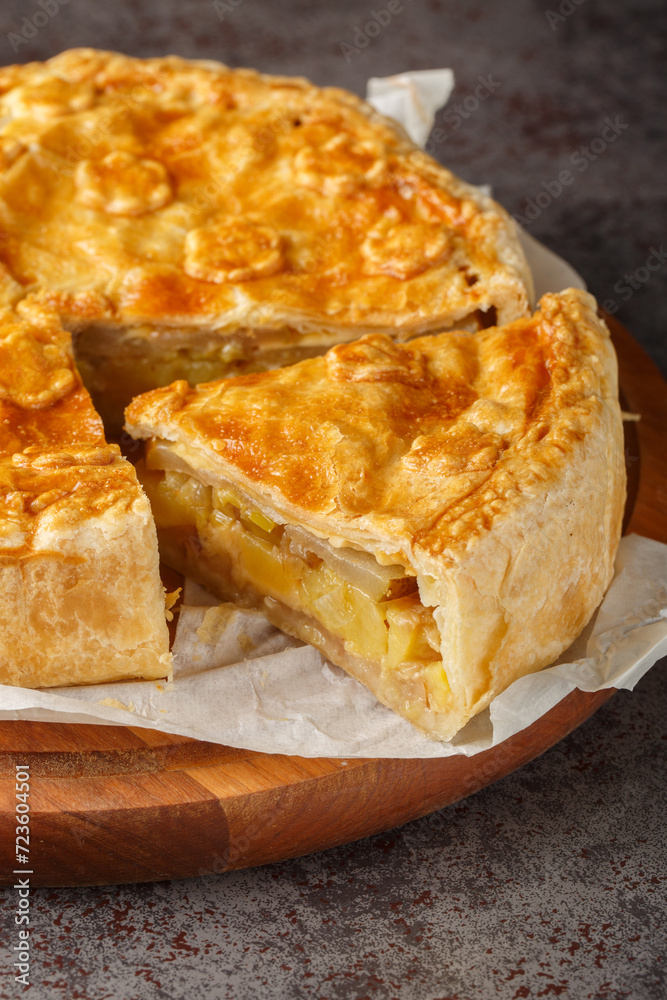 Walliser Cholera hearty pie with potatoes, apples and cheese closeup on the wooden board on the table. Vertical Walliser Cholera hearty pie with potatoes, apples and cheese closeup on the wooden board on the table. Vertical