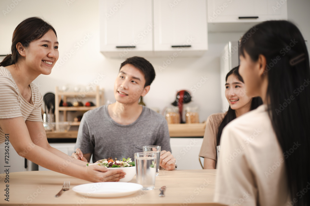 Group of Asian people friends enjoy dinner party eating food and salad on the table with talking together at home. Group of Asian people friends enjoy dinner party eating food and salad on the table with talking together at home.