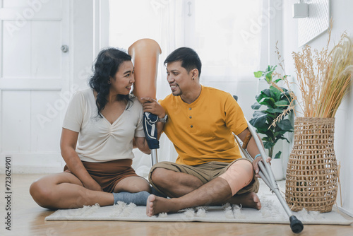 Couple bonding and smiling while sitting at home. Couple sitting on floor at home. couple with prosthetic leg sitting in living room. lover couple in casual clothes relax in living room.