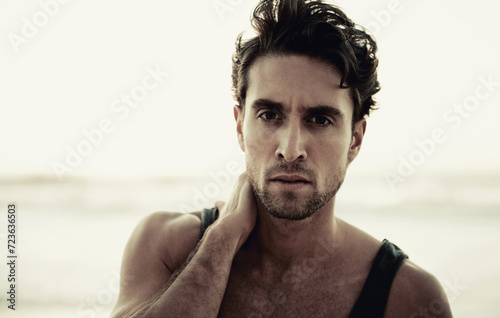 Man, portrait and travel to beach on vacation, confidence and relaxing at sea on summer holiday. Male person, serious face and tourism in Netherlands, calming ocean and peaceful environment in nature