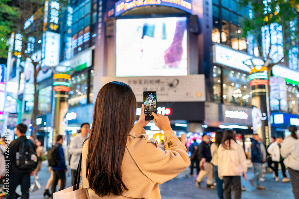 Fototapeta premium Young female tourist taking a photo of the Ximending shopping street landmark and popular attractions in Taipei, Taiwan