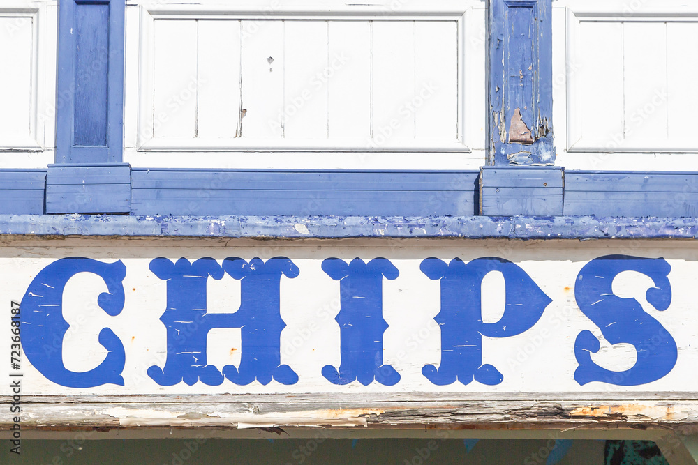 A painted sign advertising chips for sale on the sea front