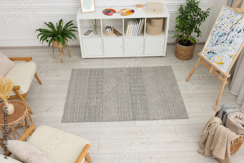 Stylish room with beautiful rug, easel and furniture, above view. Interior design