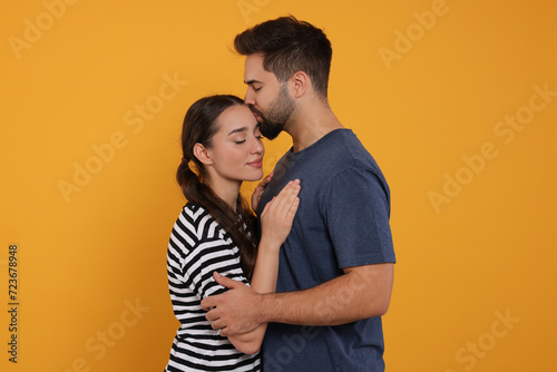 Man kissing his girlfriend on orange background © New Africa