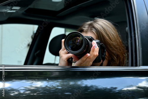 Young woman funny spying and taking photo of someone from car window. Close up