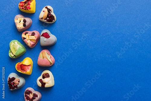 chocolate sweets in the form of a heart with fruits and nuts on a colored background. top view with space for text, holiday concept
