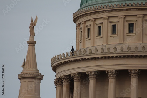 A towering building adorned with a majestic statue perched on its pinnacle.