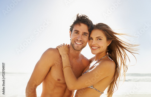 Happy couple, portrait and beach hug in nature with love, trust and support while bonding outdoor. Ocean, face and people embrace at sea for travel, adventure and summer, vacation or holiday
