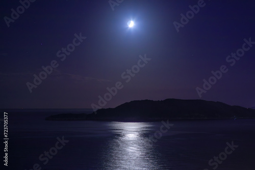 Moon in the dark sky over the island and sea