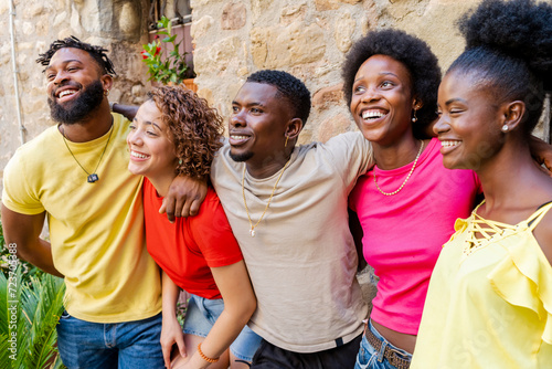 Young happy smiling multiracial group of people hugging together outdoors - Lifestyle concept with guys and girls having fun hanging out on park