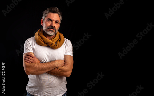 Hombre maduro vestido de forma casual mirando a cámara con seguridad, con los brazos cruzados con espacio negativo a la derecha para maquetar texto photo