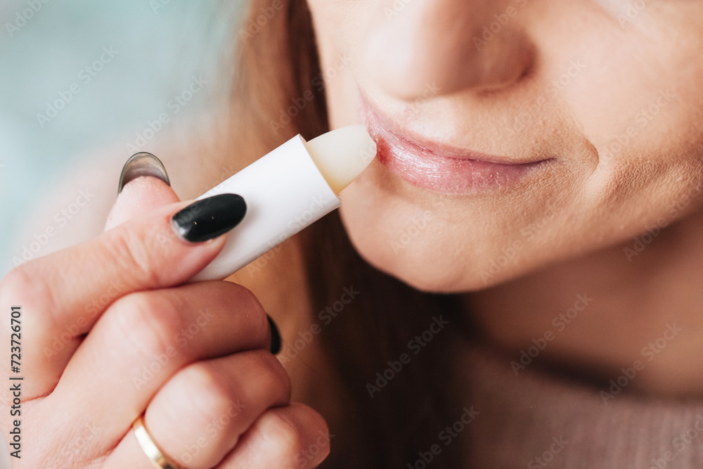 Woman using petrolatum on her mouth. Closeup lips background. Applying lip salve on lips with lipstick. Beauty background. Young girl skin care. Cosmetics for moisturize. Happy woman smile. Woman using petrolatum on her mouth. Closeup lips background. Applying lip salve on lips with lipstick. Beauty background. Young girl skin care. Cosmetics for moisturize. Happy woman smile.