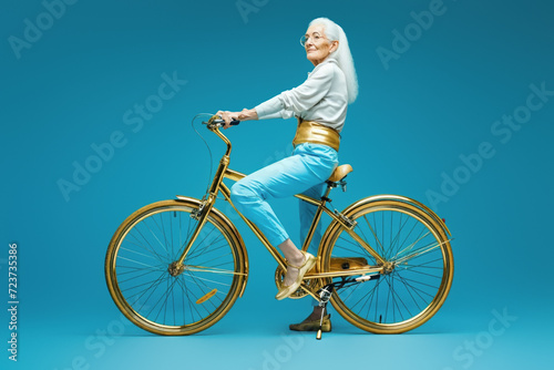 Elderly woman in sequined attire joyfully riding a classic bicycle.