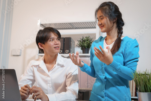 Wallpaper Mural An Asian male consultant and an African American female intern sit at a table with laptops doing paperwork together to discuss a project's financial reports. Company business collaboration concept Torontodigital.ca