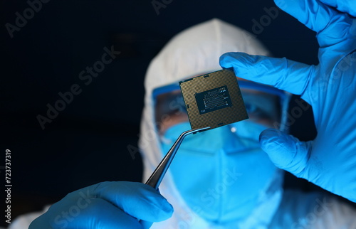 Man in uniform holds microprocessor with forceps. Software-controlled device for processing information. Repair microprocessor electronics electrical equipment. Engaged in chip implementation