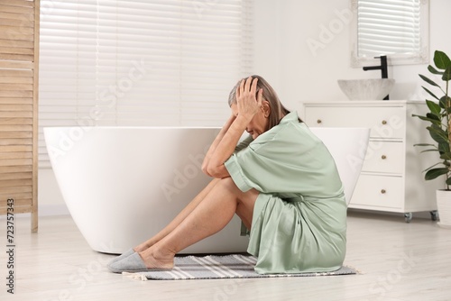Menopause. Depressed woman near bath tub in bathroom photo