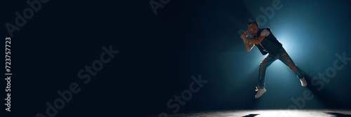 Banner. Music and drive. Man, vocalist dressed denim attire singing on stage against black background with negative space to insert text. Concept f music and dance, lifestyle, festivals, concerts. photo