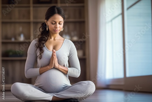 Adult Indian pregnant woman with concentrated face do meditation. New mother-to-be performs light yoga poses to relax and prepare for childbirth folding hands in prayer, copy space