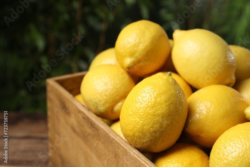 Fresh lemons in crate on wooden table  closeup