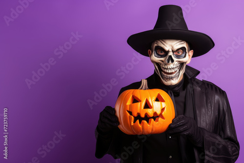 Closeup photo of man in halloween costume black cloak holding pumpkin, purple background