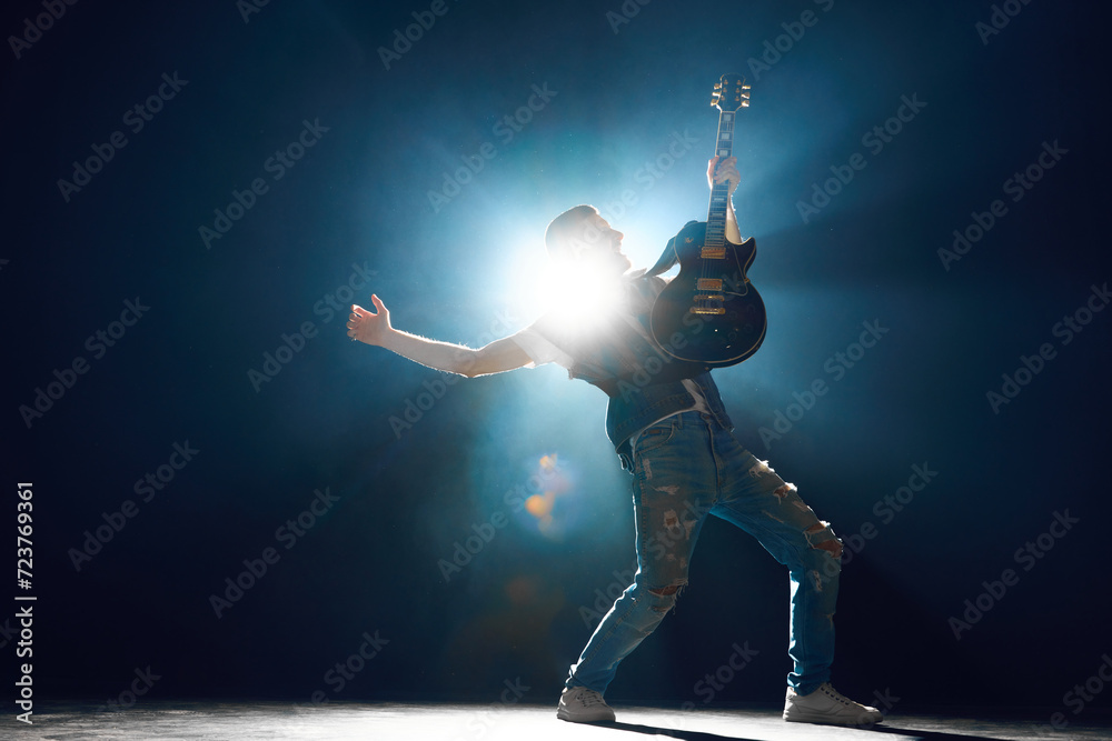 Rock performer in deep stance playing electric guitar on stage with ...