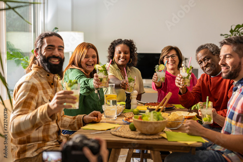 portrait of a group of multiracial and multigenerational friends with their glasses in their hands looking at the camera inviting them to toast and celebrate