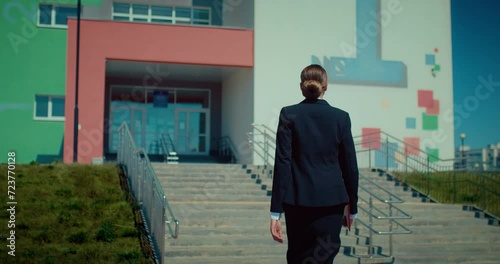 Female teacher going to school, back view, following shot of lady in classical suit, 4K, Prores