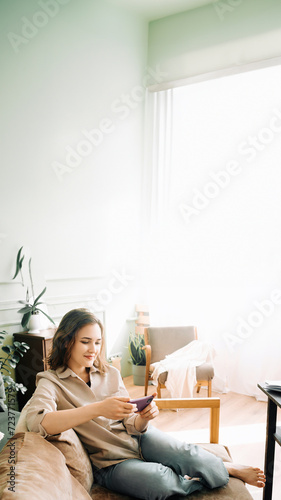 Joyful Multitasking. Smiling young woman effortlessly types on her smartphone, engages in a game, and enjoys watching a video, showcasing the versatility of modern digital interactions and entertainme photo