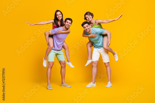 Full length photo of fellows have fun playing plane guy piggyback girls isolated vivid color background