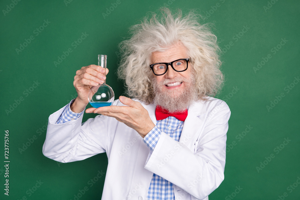 Photo of happy smiling funky funny mad scientist hold glass with liquid crazy experiment isolated on green color background