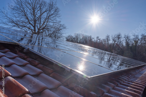 Solarmodule auf einem Hausdach reflektieren die Winter Sonne vor einem klaren blauen Himmel, Oberfranken, Deutschland