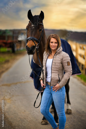 Woman with horse in portraits on a path with dramatic sky in the background.